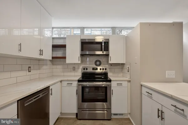 a kitchen with stainless steel appliances granite countertop a refrigerator a sink and white cabinets