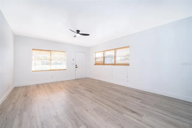 an empty room with wooden floor and windows