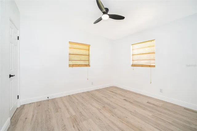an empty room with wooden floor cabinet and windows