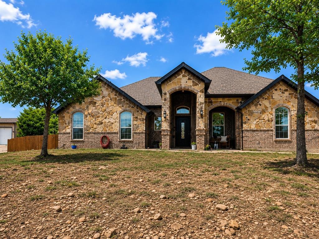 156 Cottongame Road Weatherford, TX 76088 - Photo 2 of 35 Stone and brick exterior featuring arched entryways and a dark-framed front door with decorative glass