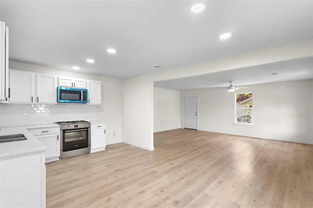 a view of a kitchen with a sink and dishwasher a stove top oven with wooden floor