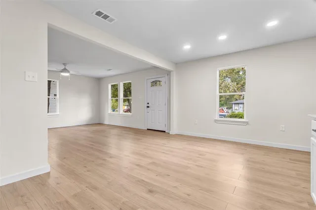 an empty room with wooden floor and windows