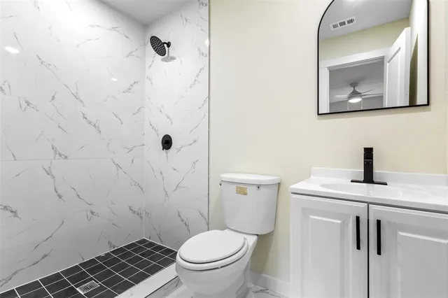 a bathroom with a granite countertop toilet sink and mirror