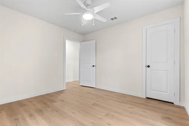an empty room with wooden floor and fan