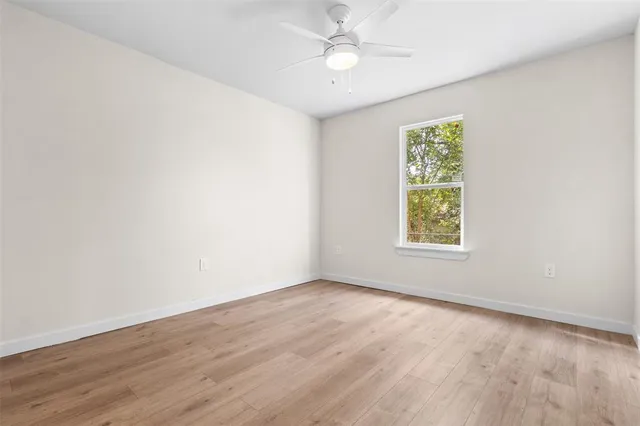 an empty room with a window and a fan