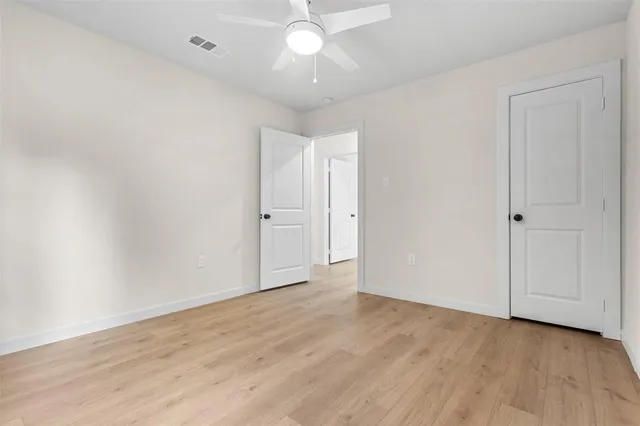 an empty room with wooden floor and fan