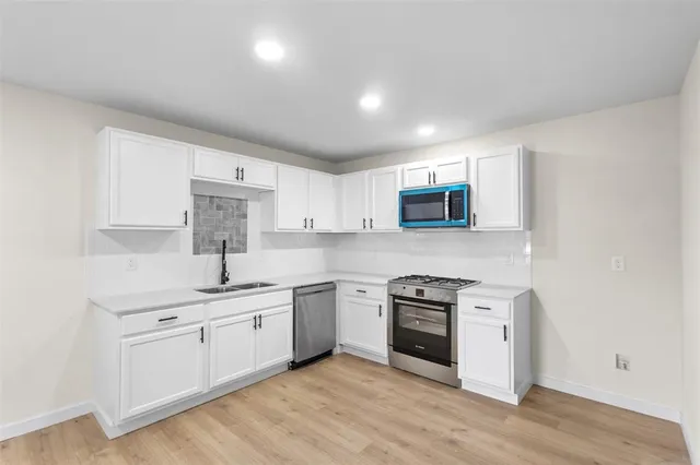 a kitchen with stainless steel appliances granite countertop a sink and cabinets with wooden floor