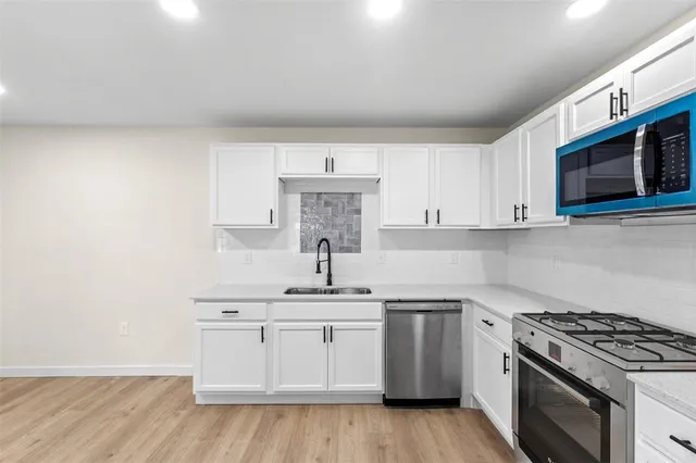 a kitchen with stainless steel appliances white cabinets and a stove top oven