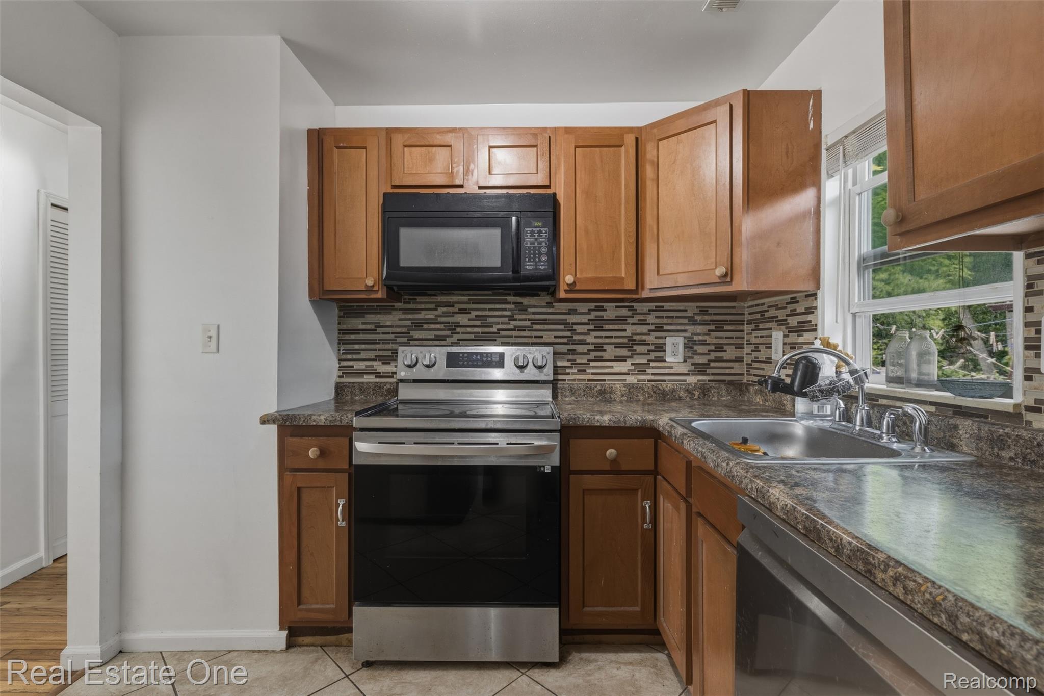 28151 Cherry Street Inkster, MI 48141 - Photo 8 of 18 Kitchen featuring wood-finish cabinetry, stainless steel appliances, a mosaic tile backsplash, and a double basin sink