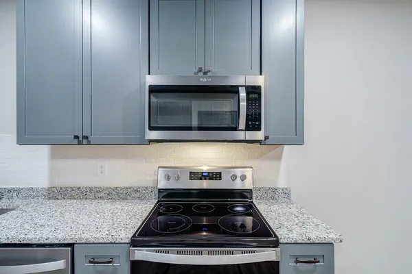 a kitchen with stainless steel appliances granite countertop white cabinets and a stove top oven