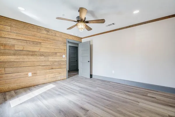 an empty room with wooden floor and a ceiling fan