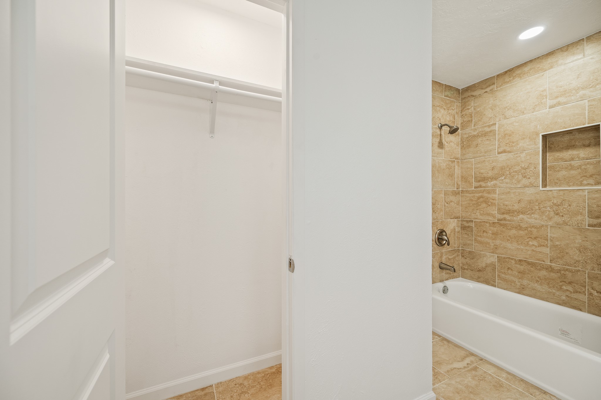 61 Hicks Loop West Cleveland, TX 77328 - Photo 26 of 38 Spacious bathroom featuring a modern shower-tub combo with elegant tilework, complemented by an adjacent walk-in closet for added convenience.