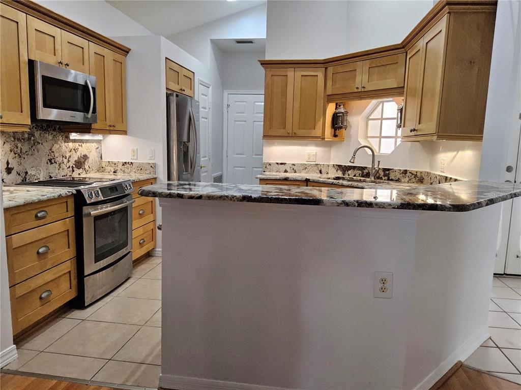 8023 St Andrews Way Mount Dora, FL 32757 - Photo 20 of 28 a kitchen with stainless steel appliances granite countertop a sink stove and microwave
