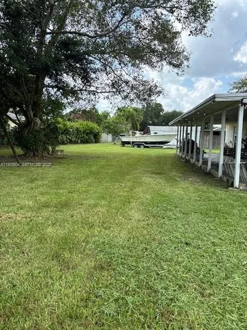 a view of a swimming pool with lawn chairs and large trees