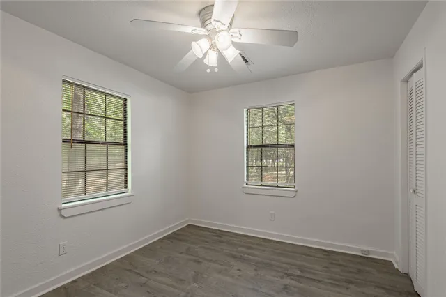a view of an empty room with a window and wooden floor