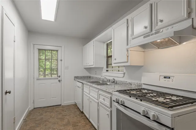 a kitchen with granite countertop stainless steel appliances sink stove and cabinets