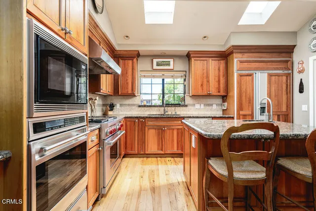 a kitchen with stainless steel appliances granite countertop a sink stove and cabinets