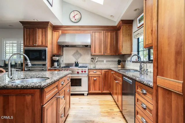 a dining hall with stainless steel appliances granite countertop a stove and a wooden cabinets