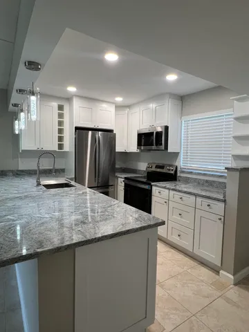 a kitchen with stainless steel appliances granite countertop a sink a stove a refrigerator and a microwave
