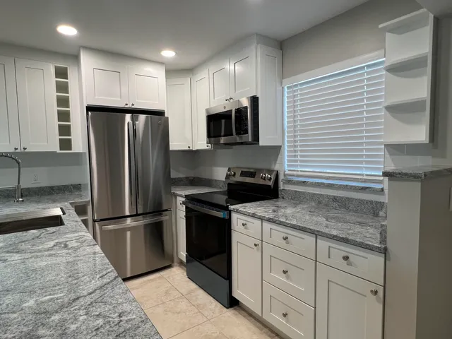 a kitchen with stainless steel appliances granite countertop a refrigerator a stove a sink and a microwave