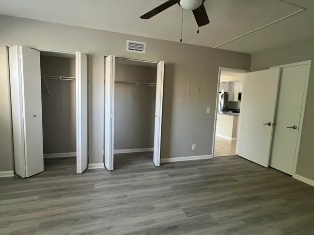 an empty room with wooden floor and a ceiling fan