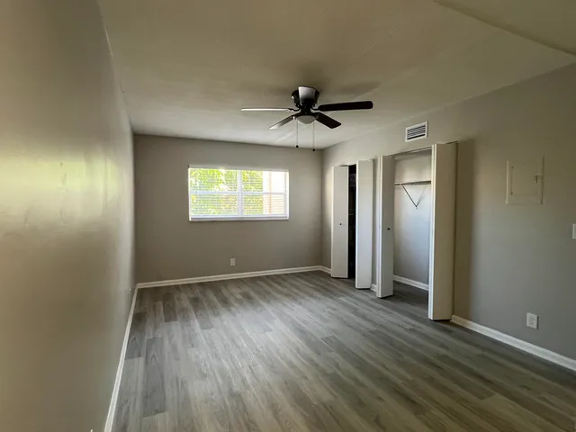 an empty room with wooden floor and windows