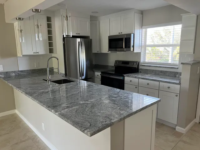 a kitchen with stainless steel appliances granite countertop a sink a stove a refrigerator a counter space and cabinets