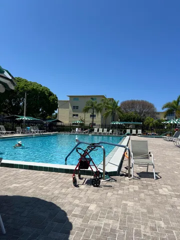 a view of swimming pool with seating area and trees in the background