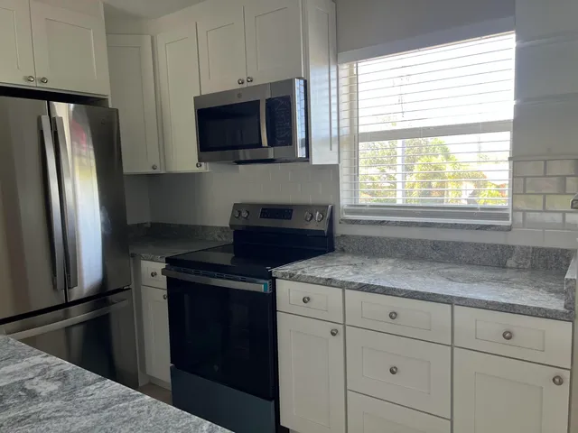 a kitchen with granite countertop a refrigerator stove and microwave