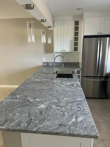 a kitchen with kitchen island granite countertop a refrigerator oven a sink and dishwasher