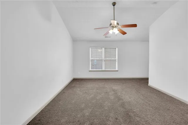 an empty room with windows and chandelier fan