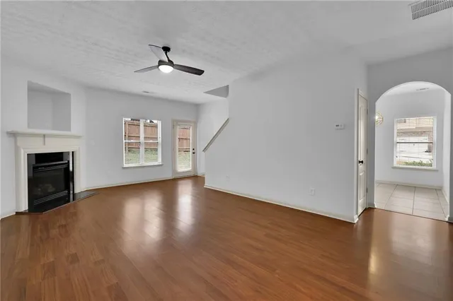 an empty room with wooden floor fireplace and windows