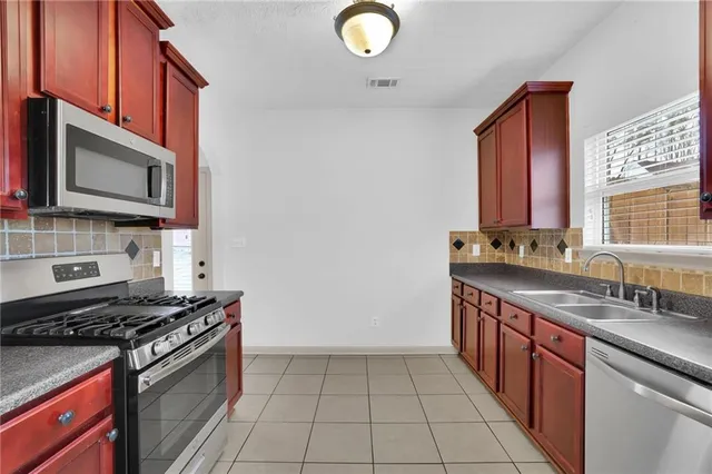a kitchen with stainless steel appliances granite countertop a stove a sink and a microwave
