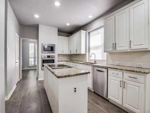 a kitchen with kitchen island granite countertop a sink a counter top space stainless steel appliances and cabinets