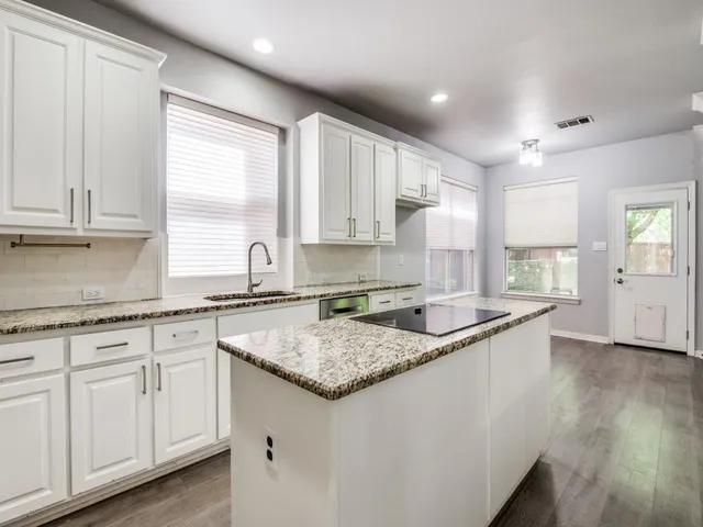 a kitchen with granite countertop white cabinets and a sink