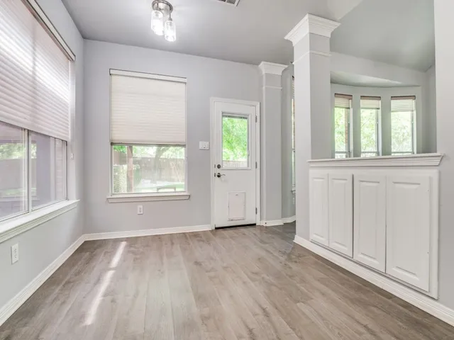 an empty room with wooden floor and windows