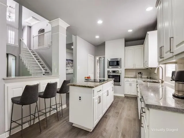 a kitchen with stainless steel appliances kitchen island granite countertop a stove a sink and a refrigerator