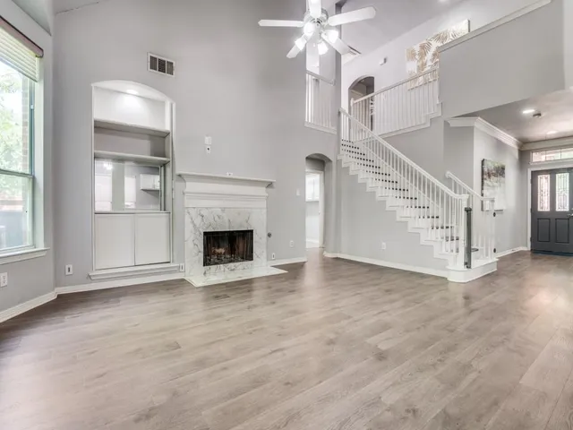 a view of an empty room with wooden floor fireplace and a window