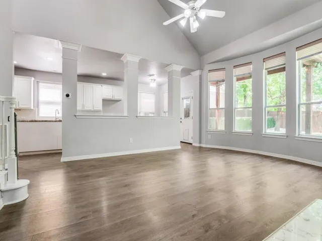 a view of an empty room with window and wooden floor