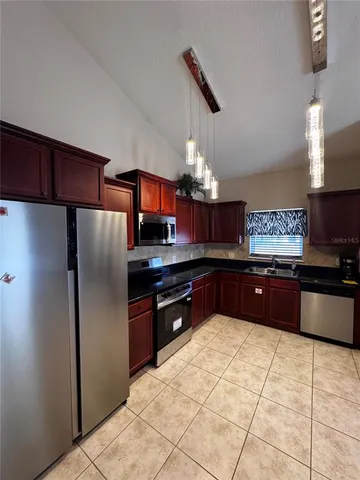 a kitchen with stainless steel appliances kitchen island granite countertop a refrigerator and a sink
