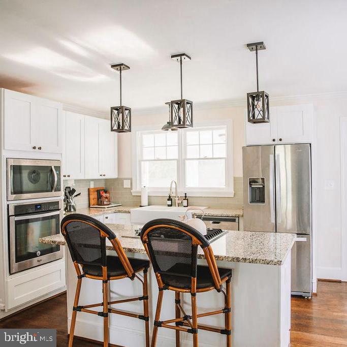 12242 Harpers Ferry Road Purcellville, VA 20132 - Photo 25 of 49 a kitchen with stainless steel appliances granite countertop a stove a refrigerator a sink a dining table and chairs with wooden floor