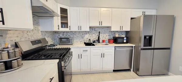 a kitchen with refrigerator a stove and white cabinets