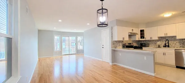 a kitchen with stainless steel appliances granite countertop a refrigerator a stove oven a sink dishwasher and white cabinets with wooden floor