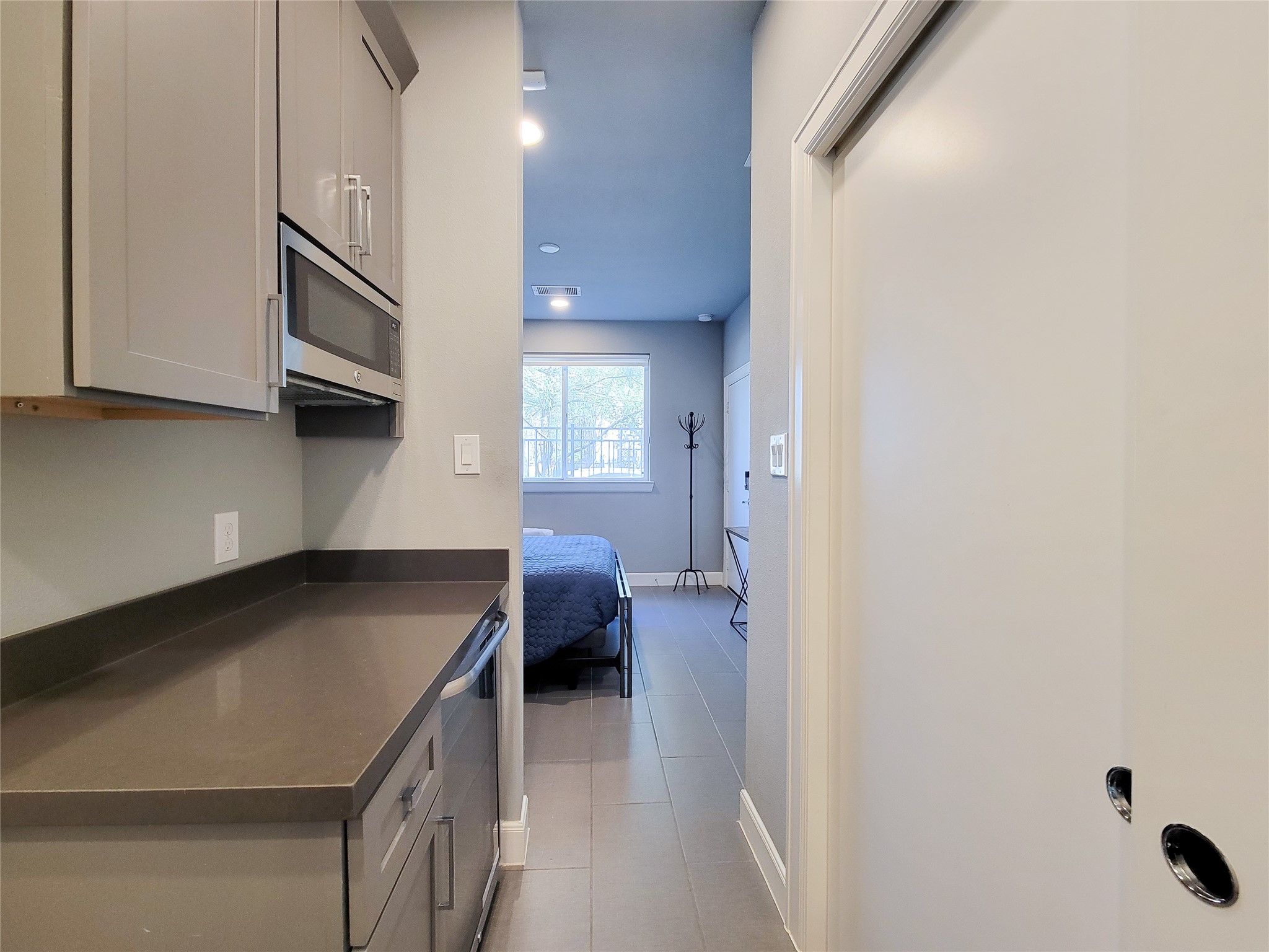 1705 Eado Point Lane Houston, TX 77003 - Photo 12 of 50 1st Floor bedroom is spacious with its sleek cabinetry with its own built-in microwave, a dark countertop, and a sliding door closet with washer/dryer hookups. The space is well-lit and has a clean, contemporary design.