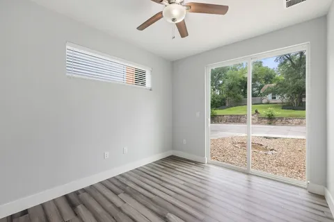 a view of an empty room with wooden floor and a window