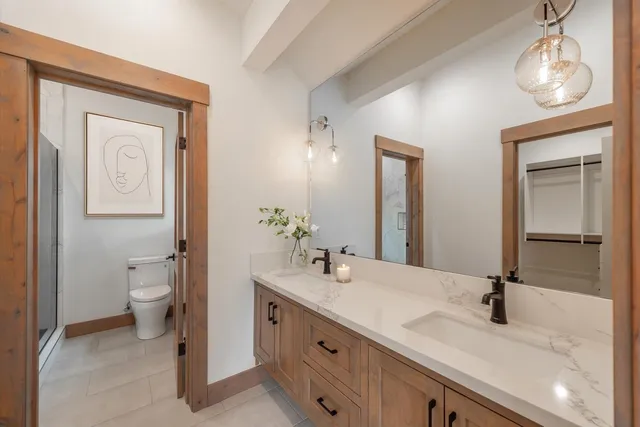 a bathroom with a double vanity sink toilet and a mirror
