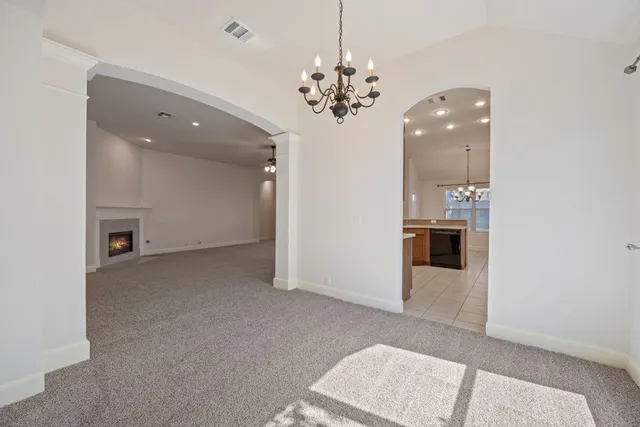 a view of a livingroom with a kitchen island the chandelier staircase and kitchen view