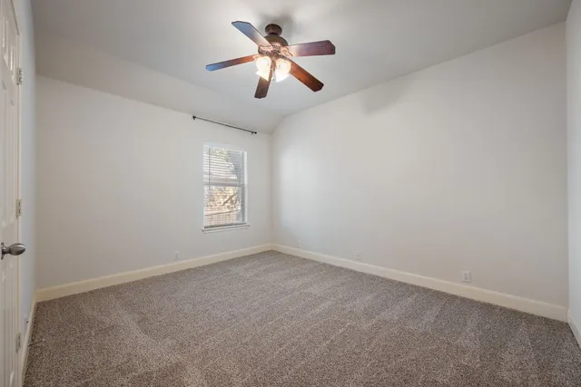 an empty room with ceiling fan and window