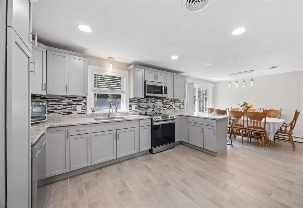 124 Lake Street Bellingham, MA 02019 - Photo 5 of 39 a kitchen with stainless steel appliances kitchen island granite countertop a stove top oven a sink a dining table and chairs