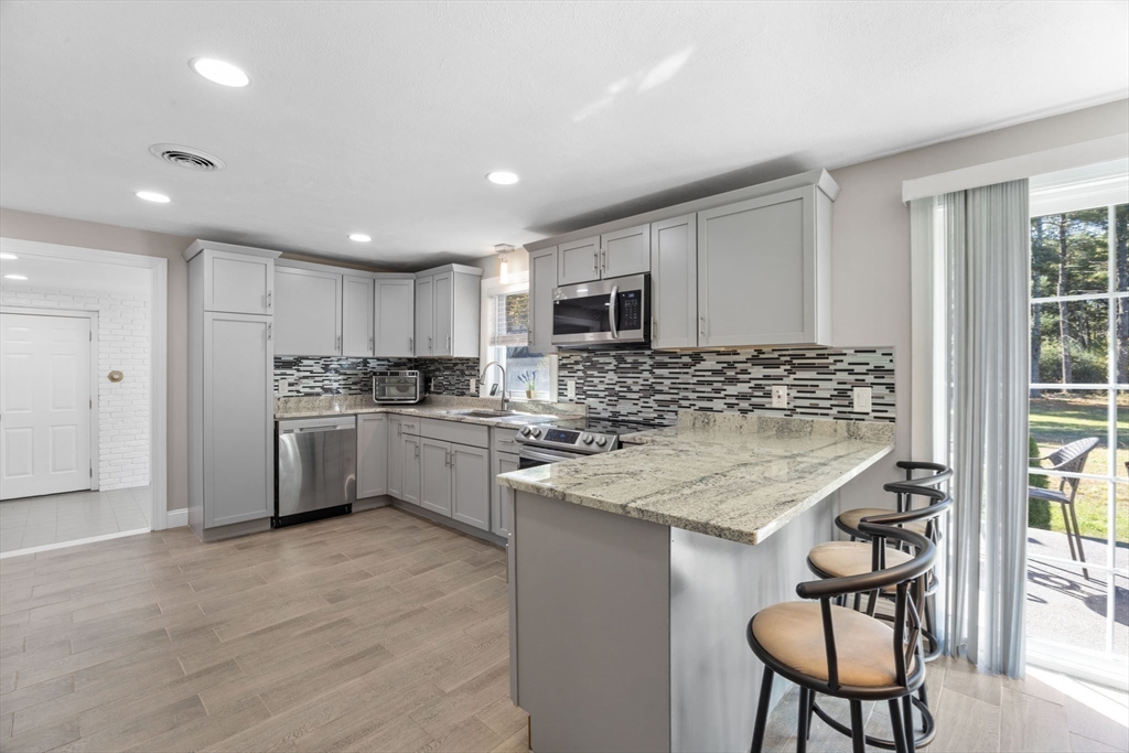 124 Lake Street Bellingham, MA 02019 - Photo 6 of 39 a kitchen with kitchen island granite countertop wooden cabinets and a refrigerator
